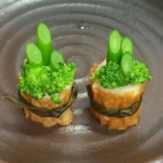 two small appetizers with broccoli on top of them sitting in a pan