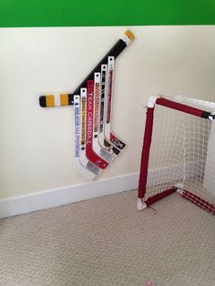 several hockey sticks hang on the wall next to a goalie's net and ball