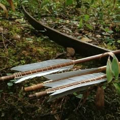 three arrows laying on the ground next to a canoe