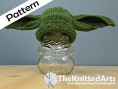 a knitted baby yoda hat sitting on top of a glass jar