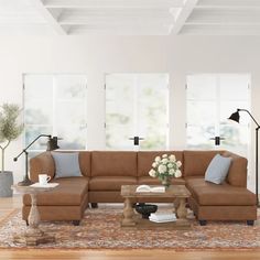 a living room with couches, tables and lamps on the floor in front of large windows