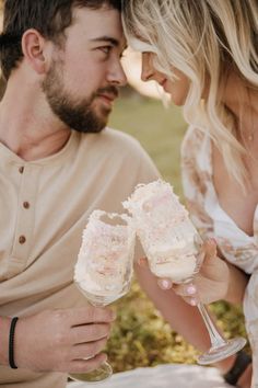 a man and woman holding wine glasses with frosting on the bottom, looking at each other