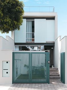 an open gate in front of a house with stairs leading up to the second floor