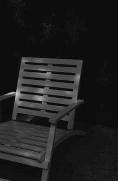 a black and white photo of a chair in the dark with light shining on it