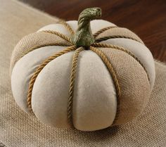 a white pumpkin sitting on top of a table next to a brown cloth covered pillow