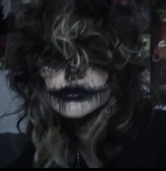 a man with long hair and makeup looks at the camera while wearing clown make - up