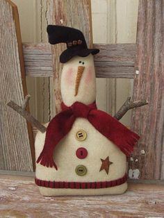 a snowman with a black hat and red scarf sitting on top of a wooden fence