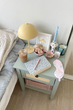 a small table with a lamp, books and other items on it next to a bed