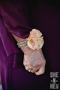 a woman in a purple dress holding onto her wrist with flowers on it's arm