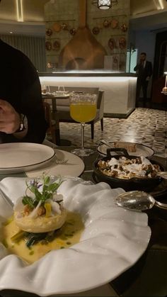 a person sitting at a table with plates and food in front of them on it