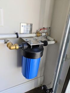 a water heater mounted to the side of a wall with pipes running down it