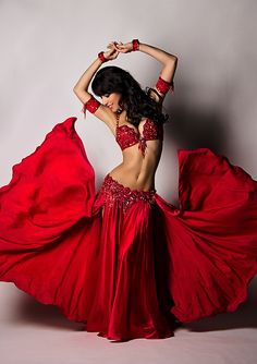 a woman in a red dress is dancing with her hands on her hips and arms behind her head