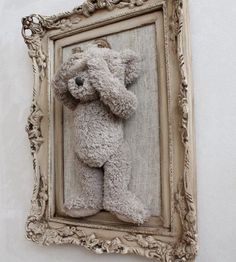 a teddy bear hanging on the side of a wall in front of a framed photo