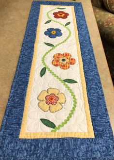 a table runner with flowers and leaves on the border is sitting next to a couch