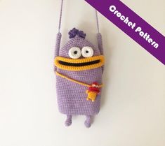 a crocheted purple bag hanging from a hook with eyes and nose on it