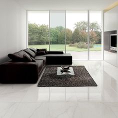 a modern living room with white walls and marble flooring, black leather couches