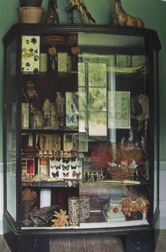 a cabinet with many items on it in a room that has green walls and wood flooring