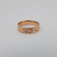 a gold wedding ring with flowers on the side and an engraved design in the middle