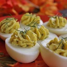 deviled eggs with dill on them sitting on a red plate