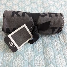 a black and gray blanket with a tag on it sitting on a bed next to a pillow