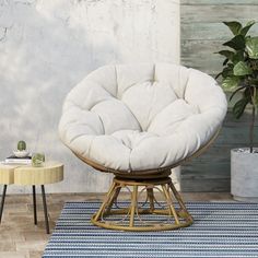 a white chair sitting on top of a rug next to a table and potted plant