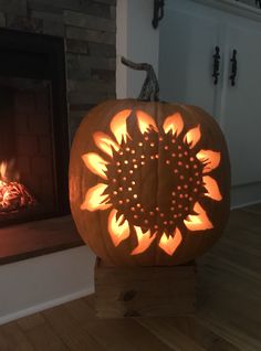 a pumpkin carved to look like a sunflower sitting in front of a fire place