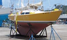 a yellow and white boat being worked on at a dock with other boats in the background