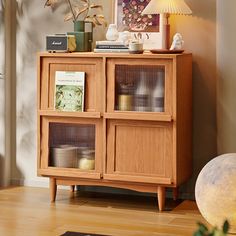 a wooden cabinet sitting on top of a hard wood floor next to a lamp and bookshelf