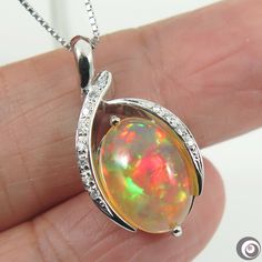 "Fine hand-crafted solid platinum (Pt.900) pendant with 0.07ctw. of sparkling natural mined accent diamonds and a large 3.676ct. of  Ethiopian flashy 'harlequin\", untreated \"fire opal\". So striking rolling flashed of rainbow colors (red, green, blue, orange gold; etc.). The necklace is also made of platinum (stamped: Pt850).  It is fine, dainty necklace, which about 0.7mm in thickness & 17.5 inches in length and can be adjust to shorten it. Style: Pendant Necklace Precious Metal: Solid Platinum (PT900) Genuine diamond: 0.07ctw. Pendant Size (L x W):  13.5mm x 25.8mm Necklace Length: 17.5 inches & adjustable. Total Weight (includes chain): 8.7 grams. Opal Type: Welo Opal. Size: 9.5 x 13.8mm Weight: 3.676ct. Color:   Beautiful array of color spectrum. Treatment: Natural (untreated). Origi Platinum Silver Necklace With Gemstone, Oval Diamond Necklace With Polished Finish For Gifts, Polished Finish Diamond Pendant Necklace Gift, Polished Finish Diamond Pendant Necklace For Gift, Hallmarked Platinum Diamond Necklace As Gift, Platinum Diamond Necklace For Gift, Platinum Oval Necklace As Gift, Silver Necklace With Bail In Fine Jewelry Style, Platinum Oval Necklace For Gifting