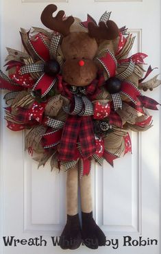 a christmas wreath with a moose head and red bow hanging on the front door,