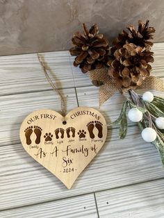 a wooden heart shaped ornament with footprints and pine cones