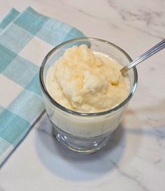 a glass bowl filled with ice cream on top of a white and blue checkered table cloth