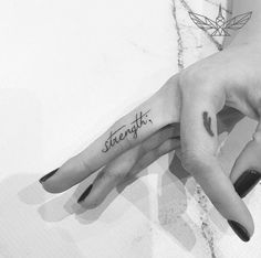 two hands holding each other with the word strength tattooed on their thumb and fingers in black ink