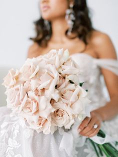 a bride holding a bouquet of flowers in her hand and looking off into the distance