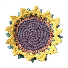 a crocheted sunflower is shown in yellow and purple, on a white background