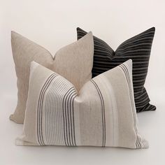 three striped pillows sitting next to each other on a white surface with black and grey stripes