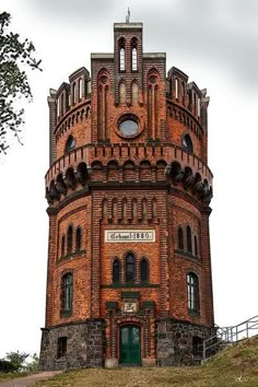 an old red brick building with a clock on it's side and stairs leading up to the top