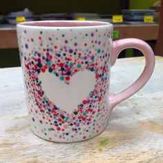 a pink coffee mug decorated with colorful confetti and a heart on the inside