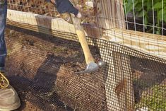 a man is holding an axue in his hand while standing next to a fence