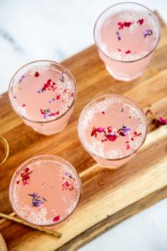 three glasses filled with pink liquid on top of a wooden cutting board