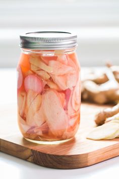 a jar filled with pickled onions on top of a wooden cutting board