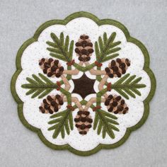 a white and green doily with pine cones on it