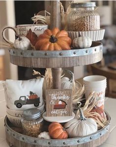 a three tiered tray filled with pumpkins and gourds on top of a table