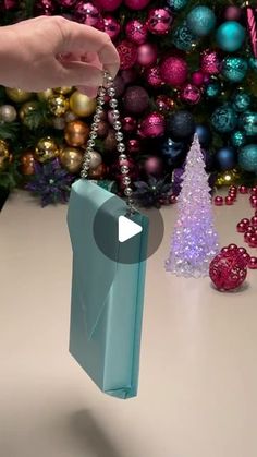 a person is holding a blue bag with a chain hanging from it and christmas decorations in the background