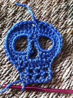 a crocheted blue skull ornament next to a knitting needle