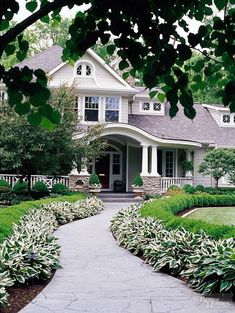 a large house surrounded by lush green trees and shrubbery in front of the entrance