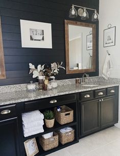 a bathroom with black cabinets and marble counter tops, white towels and pictures on the wall