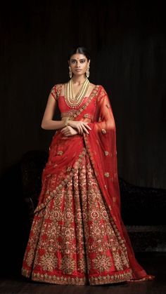 a woman in a red and gold lehenga