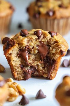 a muffin with chocolate chips and nuts on the top is half eaten from it