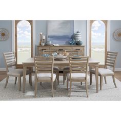 a dining room table and chairs in front of a window with an ocean scene on the wall